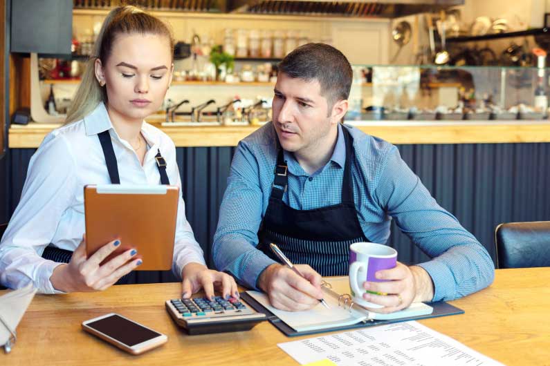Woman smiling at phone sitting behind a laptop
