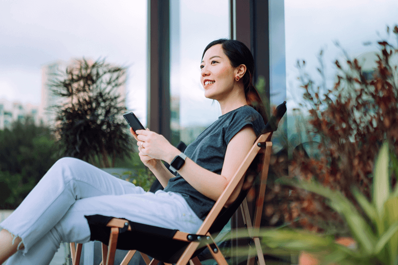 a woman sitting in a chair outside holding a phone