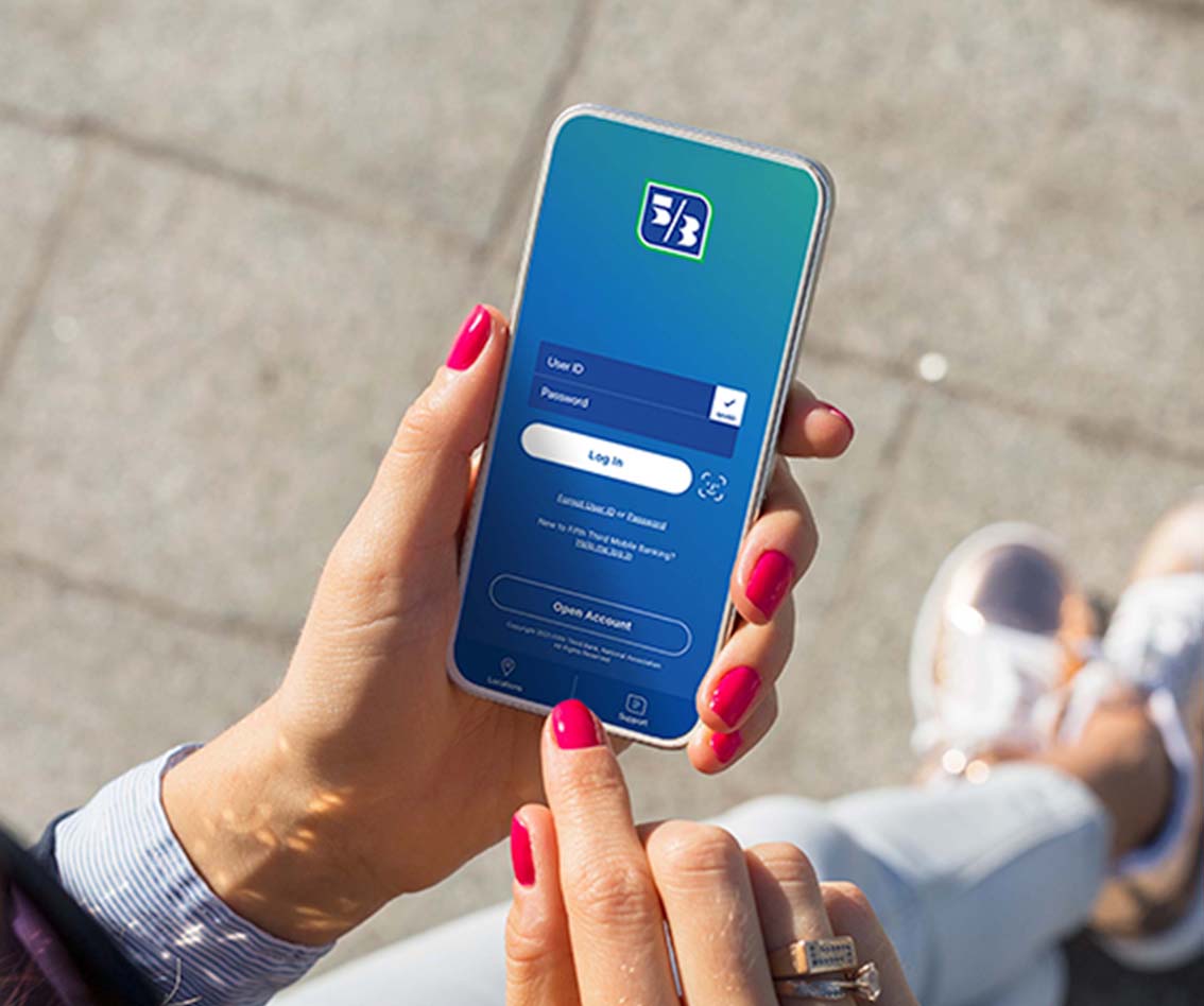 a person's hands with bright nail polish holding a phone which depicts a login screen for fifth third bank