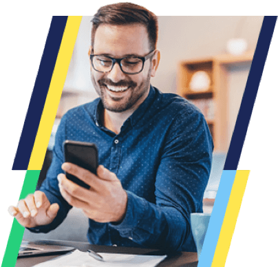 a man wearing a blue shirt and glasses smiles at the phone in his hand